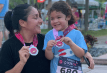 Mother and daughter holding a medal after running a race.