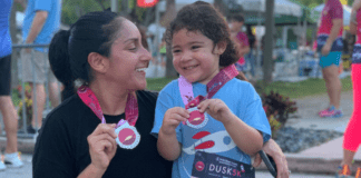Mother and daughter holding a medal after running a race.