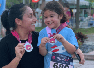 Mother and daughter holding a medal after running a race.