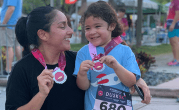 Mother and daughter holding a medal after running a race.