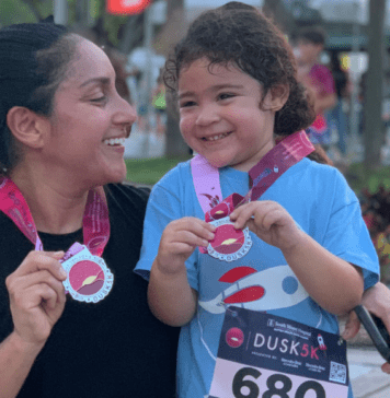 Mother and daughter holding a medal after running a race.