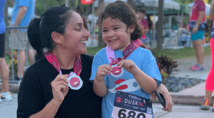 Mother and daughter holding a medal after running a race.